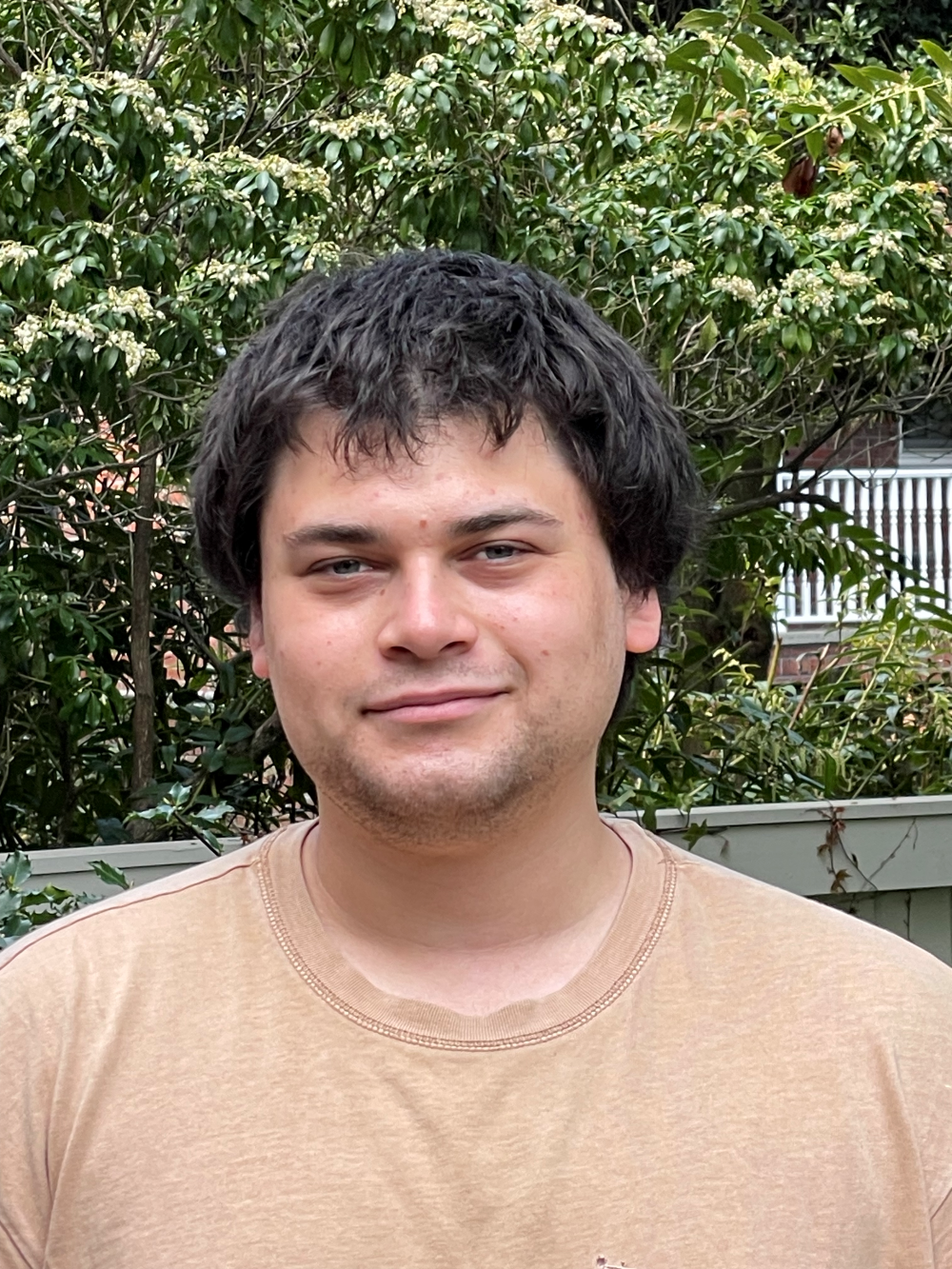 Alex Feiner smiling in front of greenery