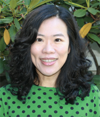 Yu-Wen Hsu smiling at the camera in front of greenery.