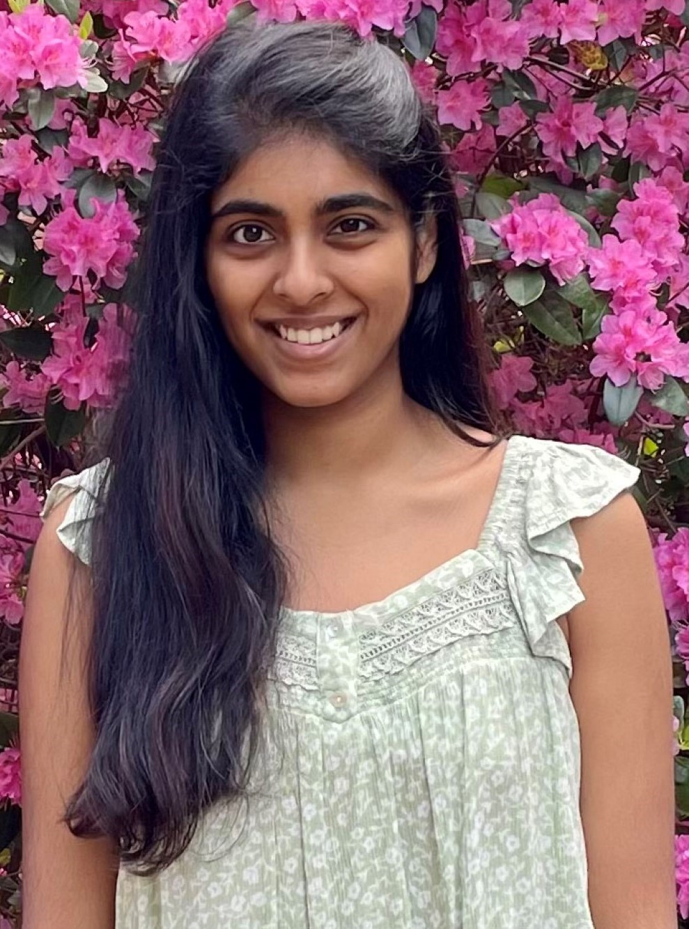 Smita Rajan smiling in front of bright pink blossoms